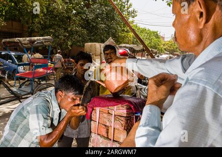 Un homme offre de l'eau froide aux travailleurs pendant la chaleur pré-mousson sur la route Khari Baoli à Old Delhi Banque D'Images