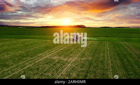 agriculteur travaillant dans le champ sur un tracteur jusqu'au coucher du soleil Banque D'Images