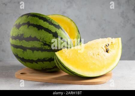 Pastèque jaune en tranches sur une planche à découper en bois sur une table. Banque D'Images