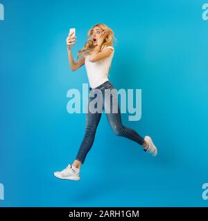 Une jeune femme choquée sautant et utilisant le téléphone Banque D'Images