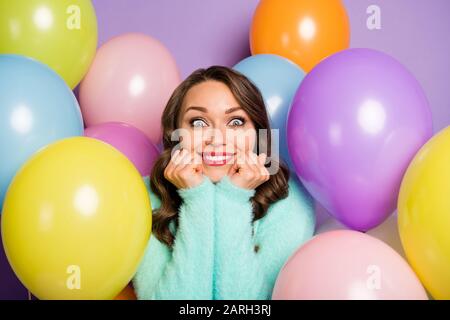 Les rêves deviennent réalité. Photo de jolie dame mains sur les joues entouré de nombreux ballons d'air colorés anniversaire fête surprise porter le pull pastel flou Banque D'Images