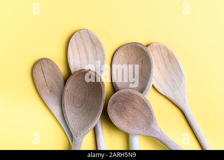 Groupe de vieilles cuillères en bois isolées sur un fond crème pâle. Banque D'Images