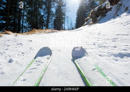 Ski tourer en montant une route enneigée à travers la forêt. Banque D'Images