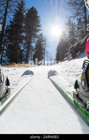 Ski tourer en montant une route enneigée à travers la forêt. Banque D'Images