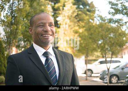 Homme d'affaires noir dans un costume regardant avec succès dans un milieu urbain Banque D'Images