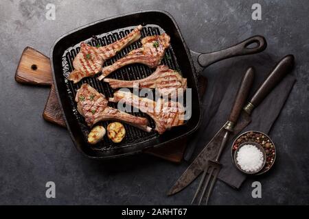 Côtes d'agneau grillées dans la poêle à frire. Carré d'agneau chaud avec épices et condiments. Vue de dessus sur la table en pierre Banque D'Images