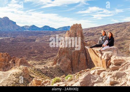 deux jeunes femmes assises sur l'affleurement rocheux au-dessus du parc national teide de tenerife Banque D'Images