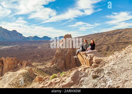 deux jeunes femmes assises sur l'affleurement rocheux au-dessus du parc national teide de tenerife Banque D'Images