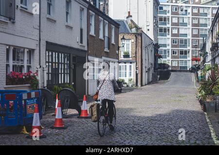 Londres/UK - 22/07/19: Une femme est en vélo dans un Mews à Bayswater, un quartier riche de la Cité de Westminster. C'est aussi l'un des mois de Londres Banque D'Images