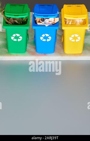 Trois bacs de recyclage à code couleur, image isométrique sur fond gris avec espace de copie. Panneau de recyclage sur les bacs, bleu, jaune et vert. Déchets de séparation Banque D'Images