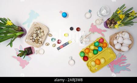 Œufs de Pâques sur table peints. Fleurs, peintures et brosses sur la table. Célébration de Pâques. Vue de dessus Banque D'Images