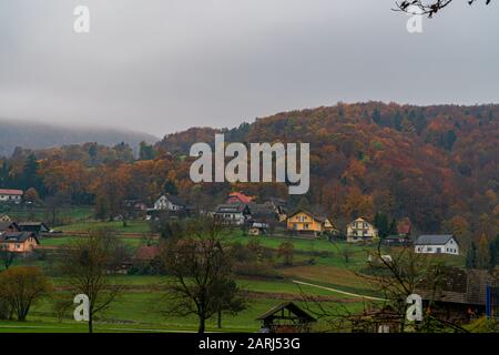 Chute dans le village alpin, les collines et la brume Banque D'Images