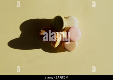 Macarons pastel de composition contemporaine sur fond de jaune clair avec ombre sombre. Banque D'Images