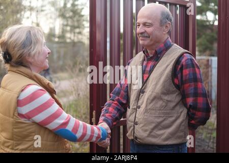 Deux agriculteurs senior femme et homme se secouent les mains et se takling l'un à l'autre le jour ensoleillé Banque D'Images