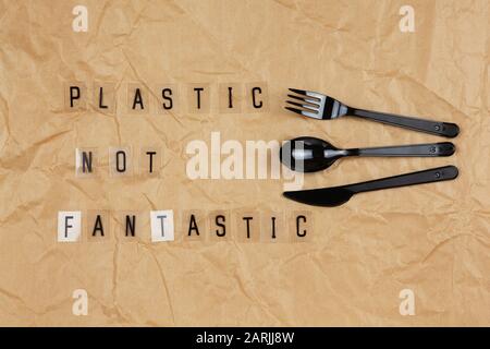 Appareils jetables noir fourchette, cuillère, couteau, phrase de lettres sur fond transparent plastique pas fantastique sur papier d'artisanat brun froissé. ECO, zéro Banque D'Images