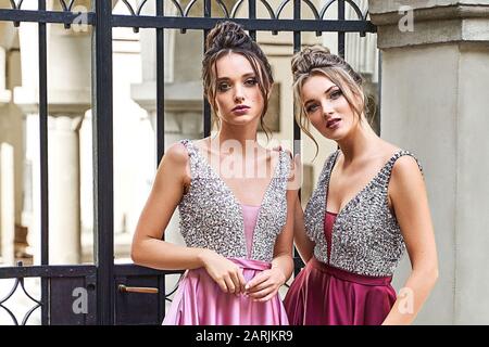 Deux belles filles mariées blondes et brunette femmes portant une élégante robe de demoiselle de demoiselle violette violette rose lylas en satin repliée avec Banque D'Images