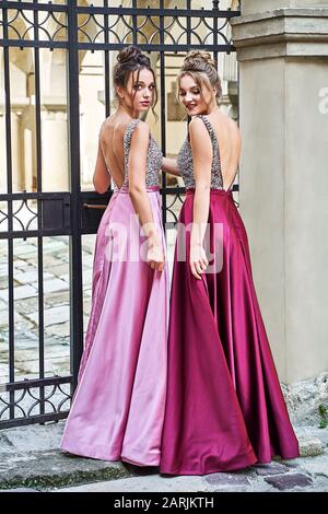 Deux belles filles mariées blondes et brunette femmes portant une élégante robe de demoiselle de demoiselle violette violette rose lylas en satin repliée avec Banque D'Images