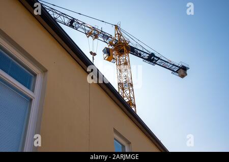 Grue tour jaune derrière bâtiment de grande hauteur. Banque D'Images