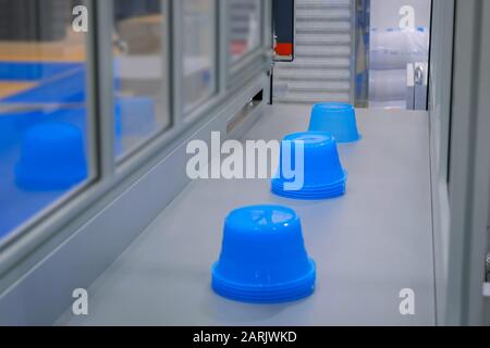 Pots bleus sur la bande transporteuse de la machine de moulage par injection plastique à l'exposition Banque D'Images