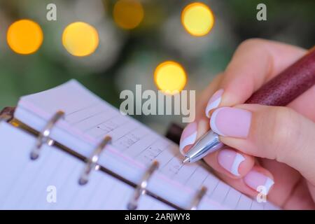 Woman hand holding pen et de l'écriture liste des tâches de l'organisateur portable vintage Banque D'Images