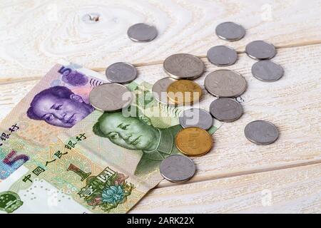 Billets et pièces de yuan chinois sur une surface en bois blanc. Papier et argent métallique chinois sur une table. Concept de richesse, de pauvreté et d'argent. Vue de face. Banque D'Images