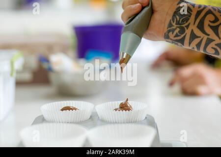 Femme chef pâtissière professionnel pâte à tartiner la pâte au chocolat dans le plat de cuisson. Banque D'Images