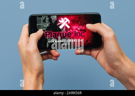 Samara, Russie -07, 29, 2019 : un jeune homme jouant Plague Inc : jeu évolué sur l'Iphone 8 Plus. Teenage boy holding un téléphone dans ses mains avec un jeu plag Banque D'Images