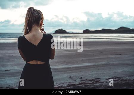 Vue arrière de la jeune femme prenant des photos de kangourous à la plage Banque D'Images