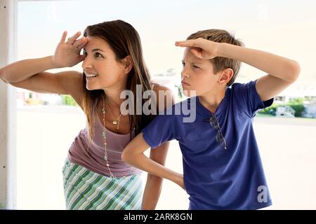 Mid-adult woman et son jeune fils s'amusant imitant les uns les autres en protégeant leurs yeux alors qu'il se trouvait sur un balcon. Banque D'Images