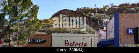 Vue panoramique sur la scène de la rue du quartier commerçant du centre-ville de Nogales, AZ, à la frontière avec MX, l'arrière-plan révèle la clôture de la frontière des lattes métalliques Banque D'Images