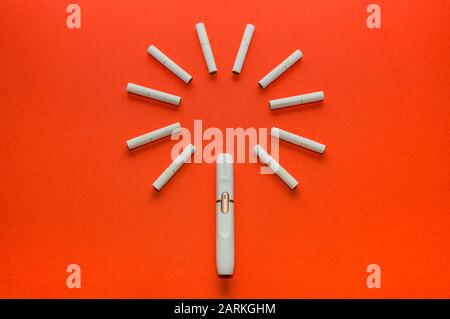 Saint-Pétersbourg, Russie - 08.08.2019: Système alternatif de tabagisme. Iqos. Support et colle sur un fond rouge. Banque D'Images