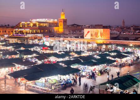 Café Argana et étals couverts de souq dans un Jemaa el-Fnaa animé au crépuscule à Marrakech, Marrakech-Safi Maroc. Banque D'Images