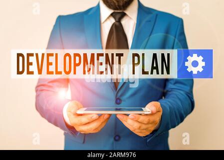 Signe texte montrant Plan de développement. Texte photo d'affaires la planification de l'élaboration d'une zone de terre Businessman in blue suite avec une cravate est titulaire Banque D'Images