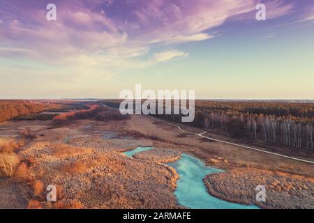 Vue aérienne sur la campagne et le ruisseau gelé le soir au coucher du soleil. Beau paysage naturel avec ciel nuageux. Banque D'Images