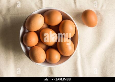 Œufs de poulet dans le bol sur un chiffon rugueux - vue sur le dessus oeufs de poulet de ferme brun photo Banque D'Images