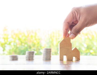 Les pièces d'économie d'argent s'empilent avec un intérêt croissant dans le parc public sur le concept de table en bois pour modèle de maison en bois investissement immobilier hypothèque financière r Banque D'Images