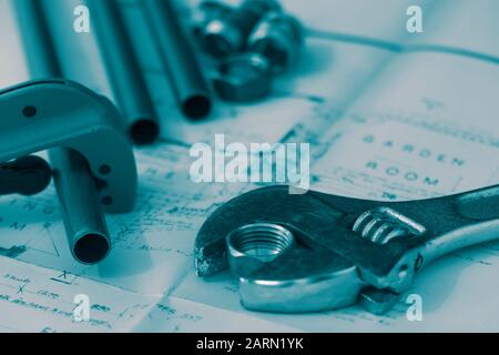 Outil de coupe de tuyaux en cuivre et clé à molette réglable sur un ensemble de plans de construction d'architecture, avec connecteurs de plomberie. Couleur de dégradé bleu Banque D'Images