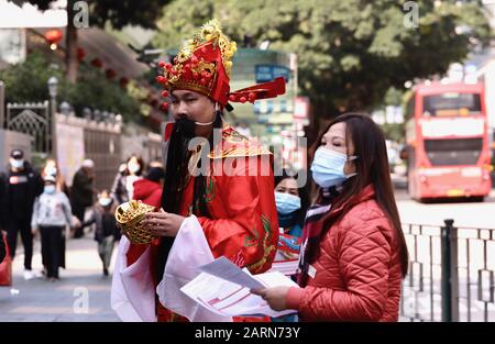 Hong Kong, CHINE. 29 janvier 2020. Un homme vêtu d'Un Chinois Assez Dieu de Fortune ( Chai-Sheng ) se trouve dans la rue offrant des « bénédictions » aux piétons avec deux femmes masquées pendant le nouvel an chinois à Hong Kong sous la menace de la propagation du Coronavirus sur le continent et à l'étranger.Jan-29, 2020 Hong Kong.ZUMA/Liau Chung-ren Credit: Liau Chung-Ren/Zuma Wire/Alay Live News Banque D'Images