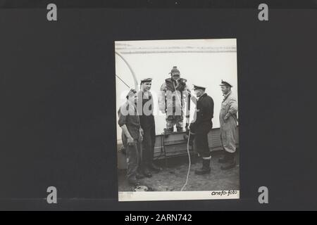 À Den Helder est pratiqué par le personnel naval belge pour l'entraînement au plongeur. L'un des Belges de plongée - un soi-disant costume de suivi, récemment utilisé par la marine néerlandaise - prêt à descendre du bateau d'entraînement de plongée. Complètement à droite l'un des autres Belges, qui est en formation pour plongeur Date: 12 septembre 1951 lieu: Den Helder, Noord-Holland mots clés: Plongeurs, marine, formations Banque D'Images