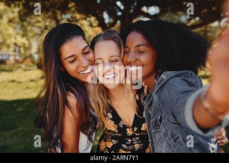 Gros portrait de souriantes femmes millénaires multiraciales rire se posent pour la photo de groupe ensemble - Groupe d'amis prenant un selfie dehors dans Banque D'Images