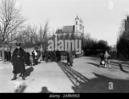 Voyage En Lituanie Vilnius. Marché sur l'aikste Lukiskiu près de l'église Saint Philippe et St Jacob. Les transporteurs avec leurs voitures attendent les clients. Au premier plan un policier Date: 1934 lieu: Lituanie, Vilnius mots clés: Églises, voitures, police, images de rue Banque D'Images