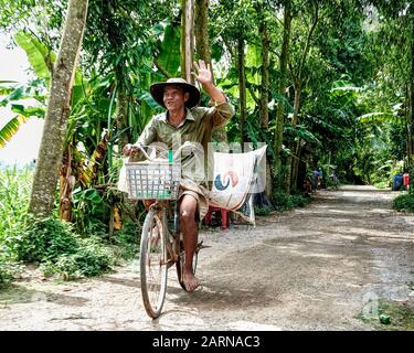 Agriculteur vietnamien en activité difficile à vélo. Les agriculteurs sont pauvres en richesse matérielle et riches en force spirituelle. Toujours une expression gaie. Banque D'Images