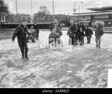 Neige et plaisir de glace à Amsterdam enfants en patinage et en traîneau dans la fontaine gelée sur Frederiksplein Date: 21 novembre 1965 lieu: Amsterdam, Noord-Holland mots clés: Glace, enfants, hiver Banque D'Images