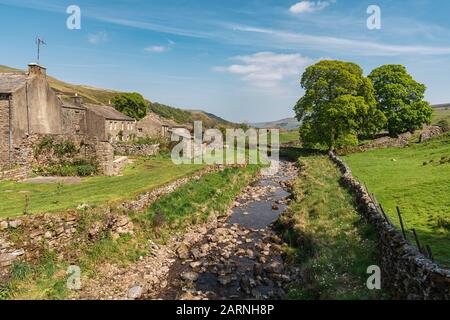 Thwaite, Yorkshire du Nord, Angleterre, Royaume-Uni - 15 mai 2019: Vue sur le Muker Beck et certaines maisons du village Banque D'Images