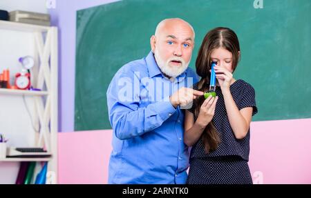 Laboratoire scientifique. Petite fille explorer la tranche de fruits. École. Microscopie. Analyse et synthèse. Élargir la connaissance du monde. Échantillon biologique. Enseignant mûr regarder par tube de loupe sur la chaux. Banque D'Images