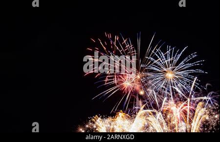 Plusieurs feux d'artifice éclatent sur des feux d'artifice pétillants d'or photographiés contre un ciel noir le 4 juillet au Minnesota Banque D'Images