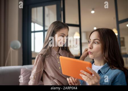 Maman communique avec sa fille et l'amuse. Banque D'Images