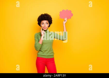 Photo de la pensée méditant la femme intéressée dans le pantalon rouge regardant dans le nuage rose de pensées pensant à de nouvelles idées isolé couleur de fond vibrante Banque D'Images