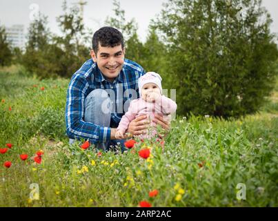 une fillette heureuse avec son père souriant dans le champ floral. Banque D'Images