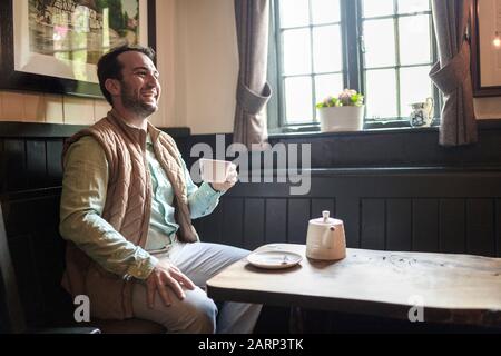 L'homme profite de son thé fraîchement préparé dans un pub anglais, au Royaume-Uni Banque D'Images